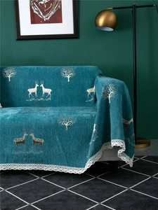 Detail of teal chenille sofa cover with reindeer patterns and white lace trim