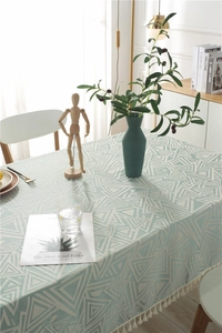 Detalle de mantel de lino verde menta con patrón de triángulos blancos y bordes de flecos