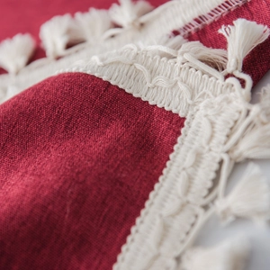 Solid burgundy tablecloth with white macrame tassels and premium linen texture