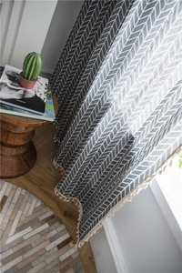 Detail of grey geometric pattern curtains with elegant off-white tassel fringe trim