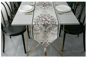 Detailed texture of white chenille table runner with pink roses and brown tassel accent