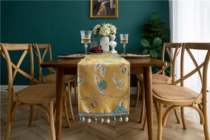 Close-up of yellow floral table runner featuring elegant lace trim and bead tassels
