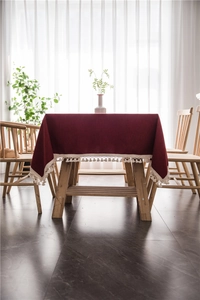 Detail of burgundy rectangular tablecloth with elegant white tassel ball fringe edges