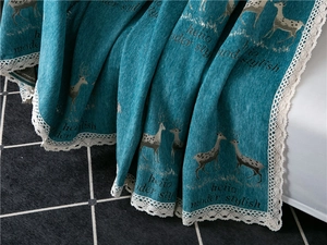 Detail of thick chenille sofa cover with teal fabric, deer pattern and white lace trim