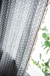 Close-up of geometric grey herringbone curtain fabric featuring delicate fringe edges