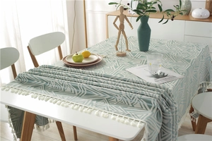 Detalle de patrones geométricos verde claro y flecos blancos densos en el mantel de mesa
