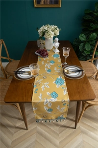Detail of floral table runner with colorful bead tassels and elegant drape on wood table
