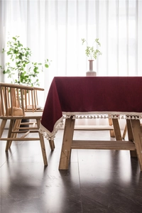 Close-up of burgundy woven tablecloth with elegant off-white tassel fringe detailing