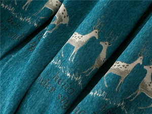 Close-up of thick blue chenille fabric with white deer pattern and modern art lettering