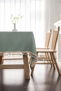 Close-up of sage green tablecloth with elegant beige fringe tassels on wooden table