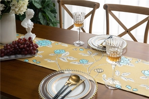 Detailed view of yellow floral polyester table runner set on dark wooden dining table