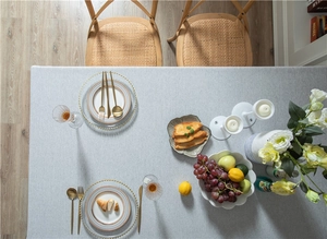 Flat lay of modern grey linen-look tablecloth with elegant gold cutlery and fresh fruit