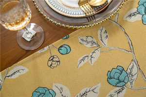 Macro view of thick polyester table runner with yellow jacquard floral patterns and tassels