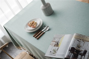 Close-up of mint green textured tablecloth featuring elegant cream tassel ball trim