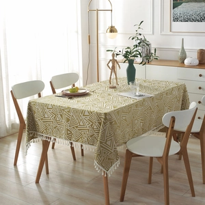 Mantel geométrico de triángulos verde y beige con flecos blancos sobre mesa de madera