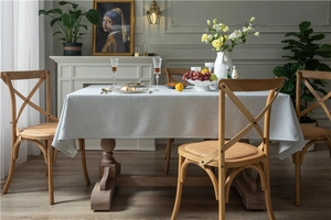 Close-up of thick beige linen-textured rectangular tablecloth in a warm dining setting