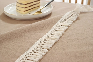 Detailaufnahme der khakifarbenen Tischdecke aus Baumwolle mit weißen Quastenfransen