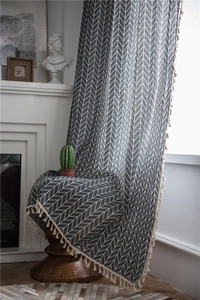 Detail of gray geometric herringbone curtain with cream white decorative tassels on the edge