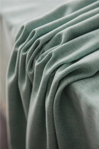 Macro shot of mint green fabric showing fine knit texture and elegant draping ripples