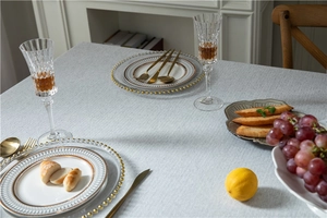 Detail of light gray linen-textured tablecloth on dining table with elegant tableware