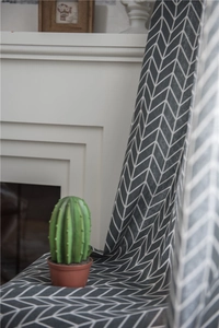 Detail of dark grey herringbone patterned fabric curtain hanging near a white fireplace