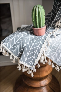 Detail of grey herringbone pattern polyester cotton fabric with white woven tassel edges