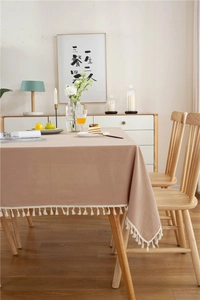 Detail einer minimalistischen braunen Baumwolltischdecke mit weißen Quastenkanten