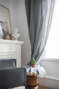 Close-up of dark grey chevron pattern curtain with off-white tassel fringe detailing