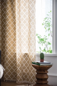 Gelber Vorhang mit geometrischem Rautenmuster und eleganten weißen Quasten im Detail