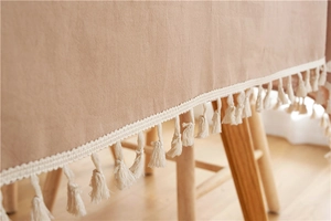 Nahaufnahme einer modernen khakifarbenen Tischdecke aus Baumwolle mit weißen Quasten