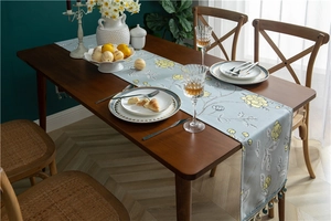 Detailed close-up of light blue floral table runner with elegant beaded tassel fringe