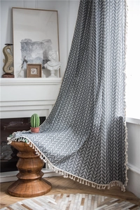 Detail of grey herringbone pattern fabric with elegant cream tassels on the edge