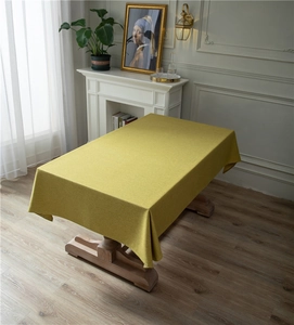 Detail of warm yellow rectangular tablecloth with thick linen texture on a wooden table