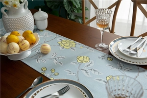 Detail of light blue table runner with yellow floral patterns on a dark wood table