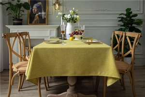 Close-up of lime yellow linen-textured tablecloth on a wooden dining table in a cozy room