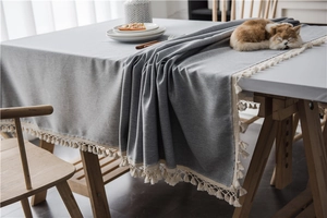 Close-up of grey rectangular tablecloth with white pom-pom tassel fringe details