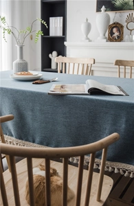 Close-up of deep blue linen textured tablecloth with elegant white fringe tassel detailing
