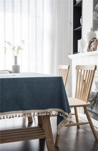 Detail of dark blue linen tablecloth featuring cream lace edges and fringe tassels