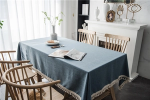 Detailed view of blue tablecloth fabric with elegant white tassel fringe and twill texture