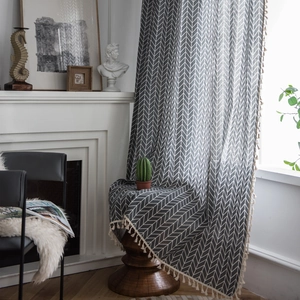 Dark grey herringbone cotton curtain with cream tassels draped in an artistic home setting