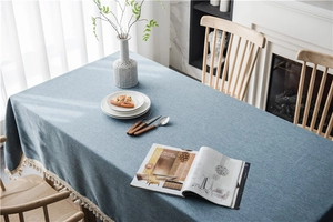 Detailed view of grey-blue woven tablecloth with elegant white tassel fringe edges