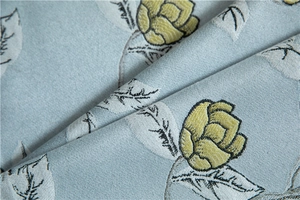 Macro detail of polyester table runner featuring elegant yellow buds and silver leaf motifs