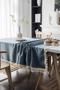 Close-up of blue textured tablecloth with elegant white fringe tassel edges for dining tables