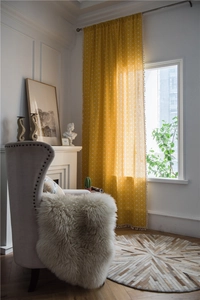 Detail of yellow geometric pattern curtain with decorative white cotton fringe trim