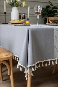 Close-up of grey jacquard tablecloth featuring delicate beige fringe and geometric patterns