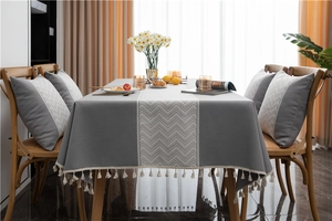 Close-up of grey jacquard tablecloth featuring white wave patterns and elegant fringe trim
