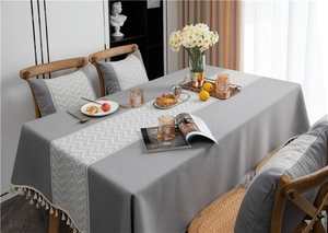 Detail of grey jacquard tablecloth with white chevron pattern and fringed edges on table