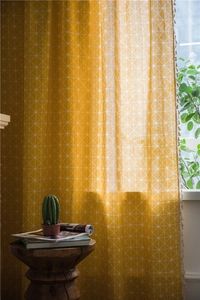 Detail of yellow checkered curtain with geometric mesh pattern and beige tassels