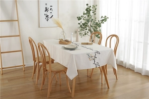Detail of embroidered beige linen tablecloth with floral pattern and elegant script text