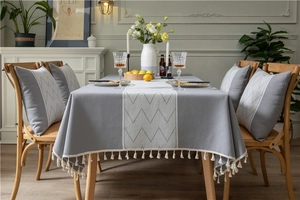 Detail of grey geometric jacquard tablecloth with white mountain patterns and tassel fringe